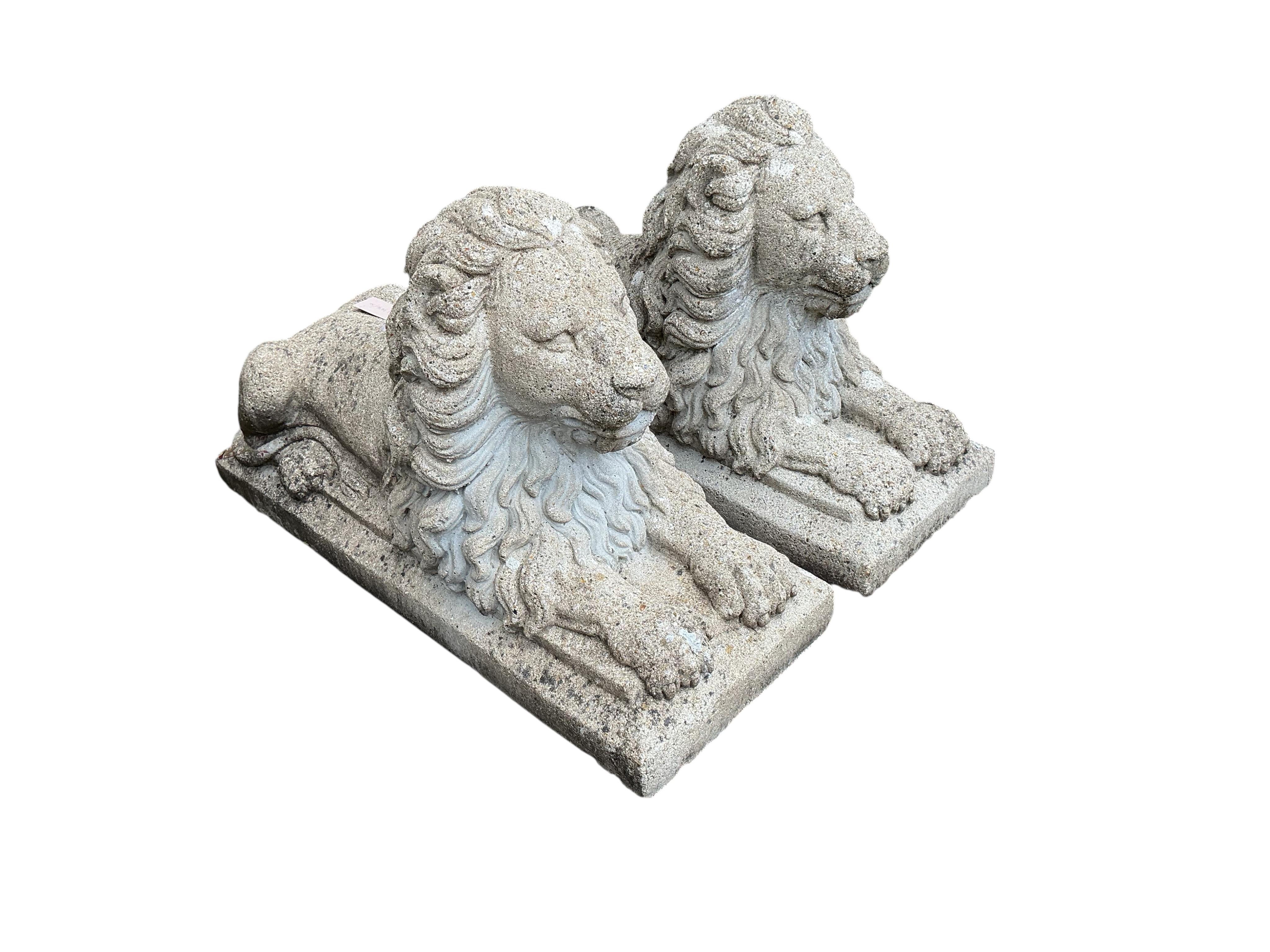 A pair of reconstituted stone lion garden ornaments, length 81cm, height 50cm